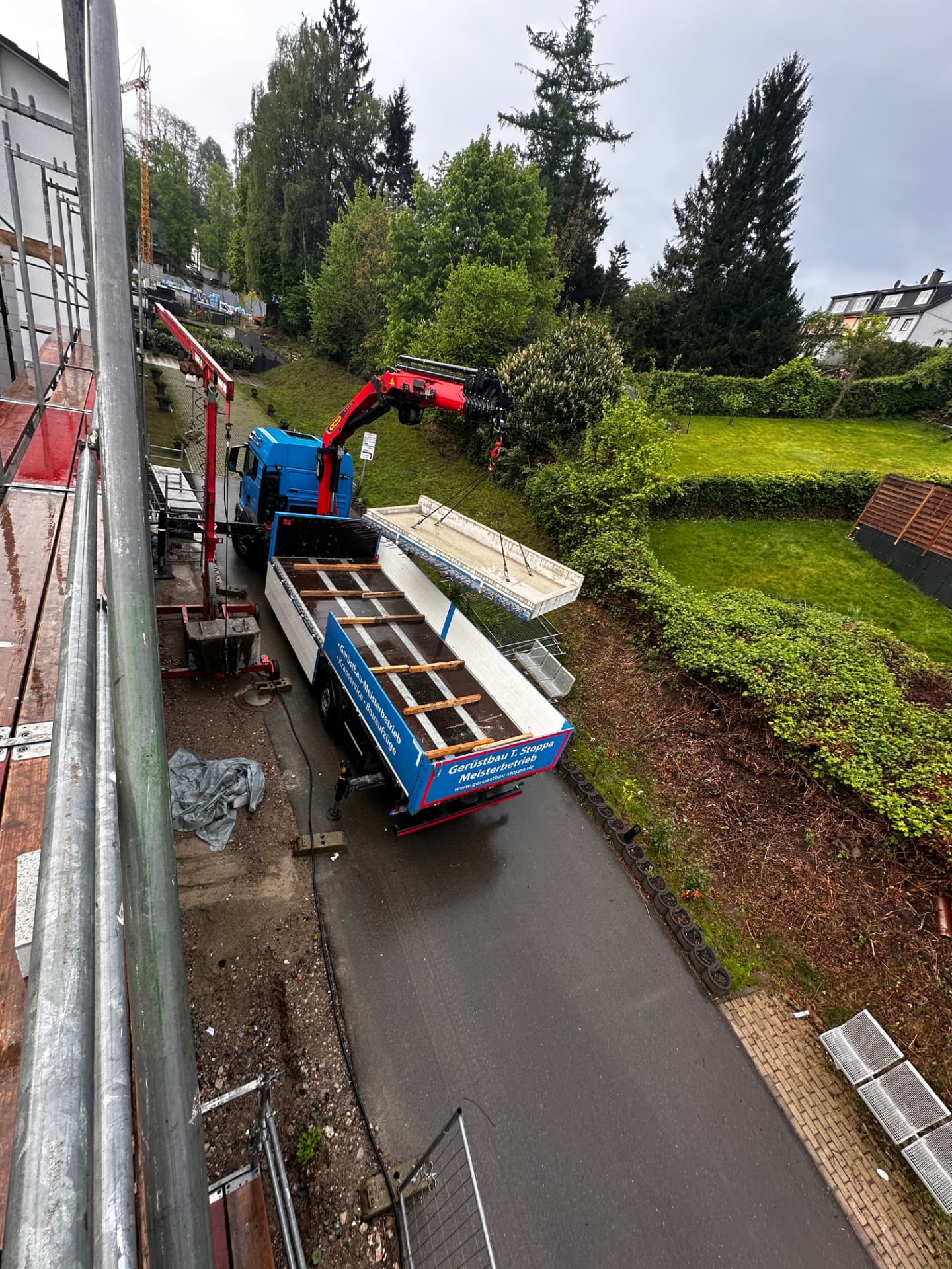 Gerüstbau-Stoppa-Lkw mit Ladekran entlädt Gerüstmaterial auf einer Baustelle