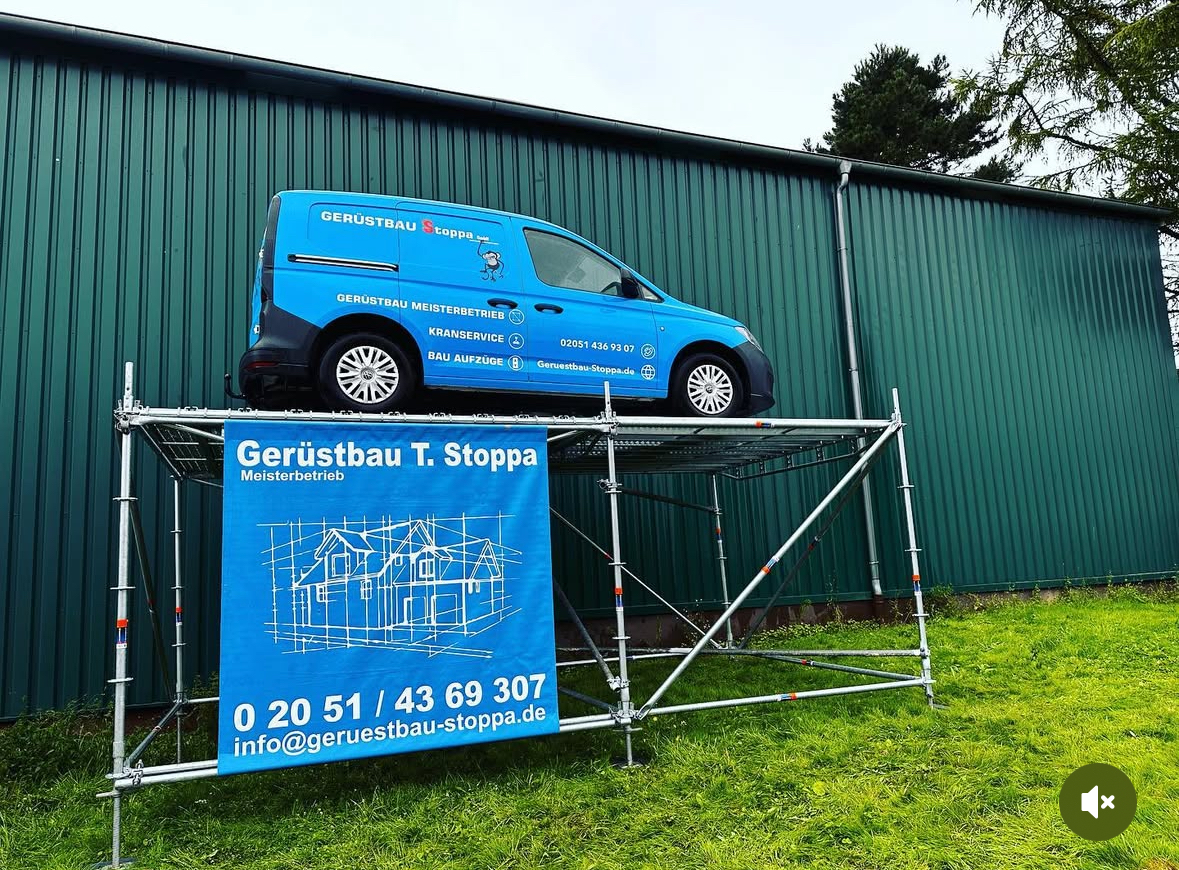 Werbeturm aus Gerüst mit blauem Stoppa-Werbebanner, darauf der Stoppa-Transporter – ein Gerüst, das Lasten trägt