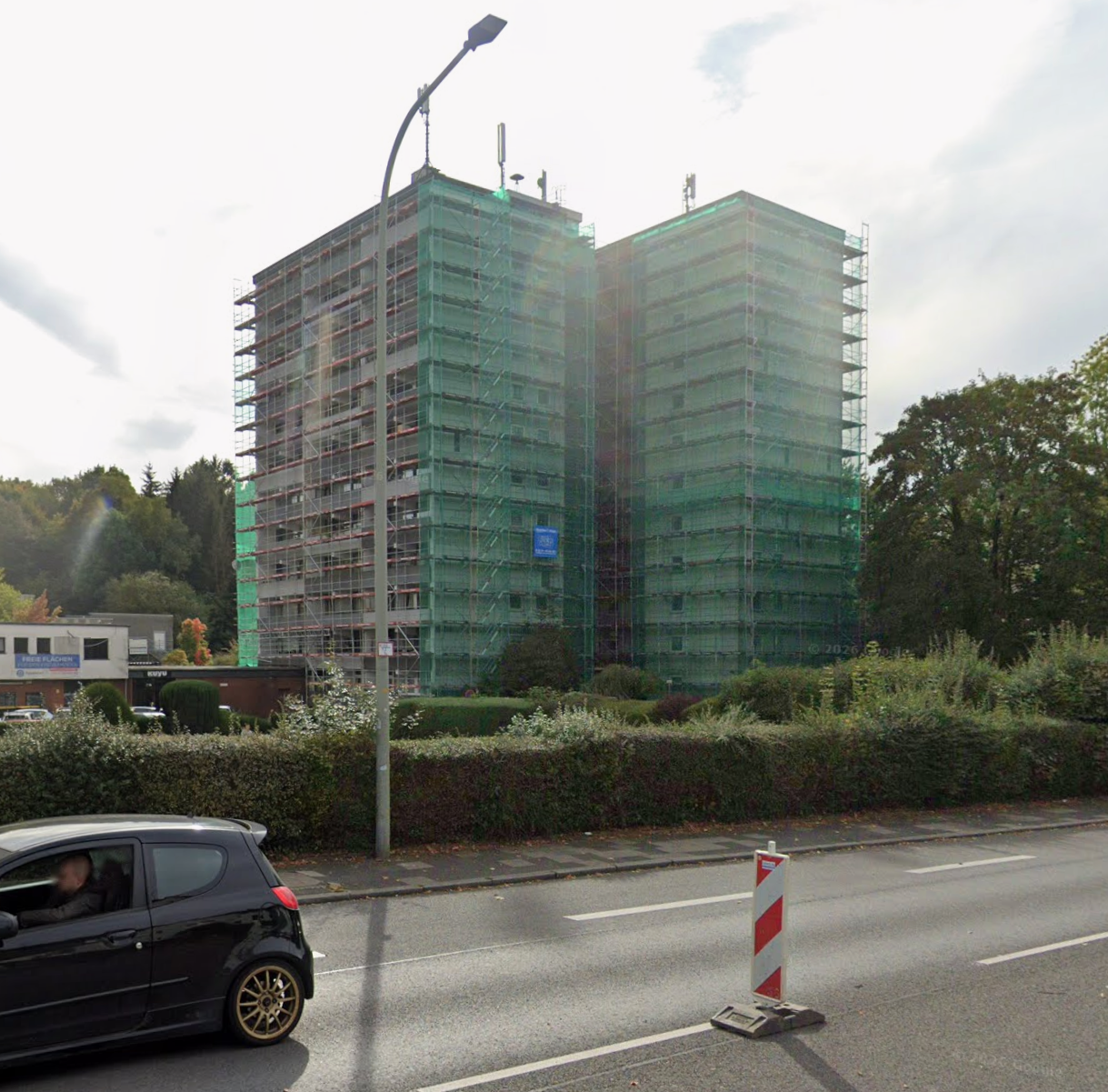 Zwei voll eingegrüstete Wohnhochhäuser in Wülfrath mit grünen Schutznetzen und blauem Stoppa-Banner