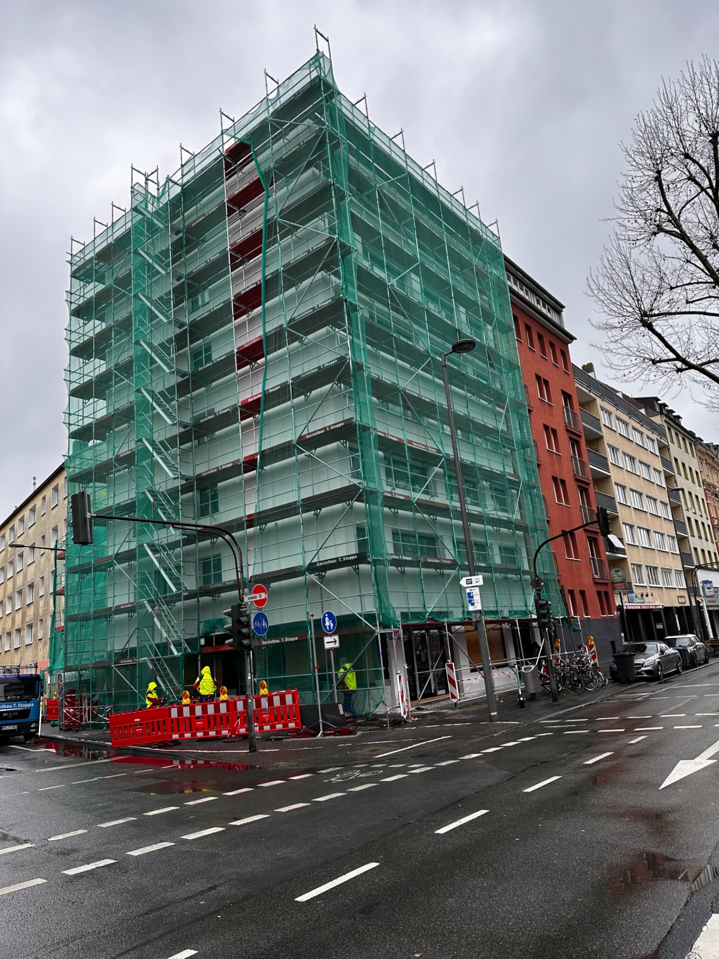 Wohn- und Geschäftshaus am Hansaring in Köln, vollflächig eingegrüstet mit grünen Staubschutznetzen von Gerüstbau Stoppa