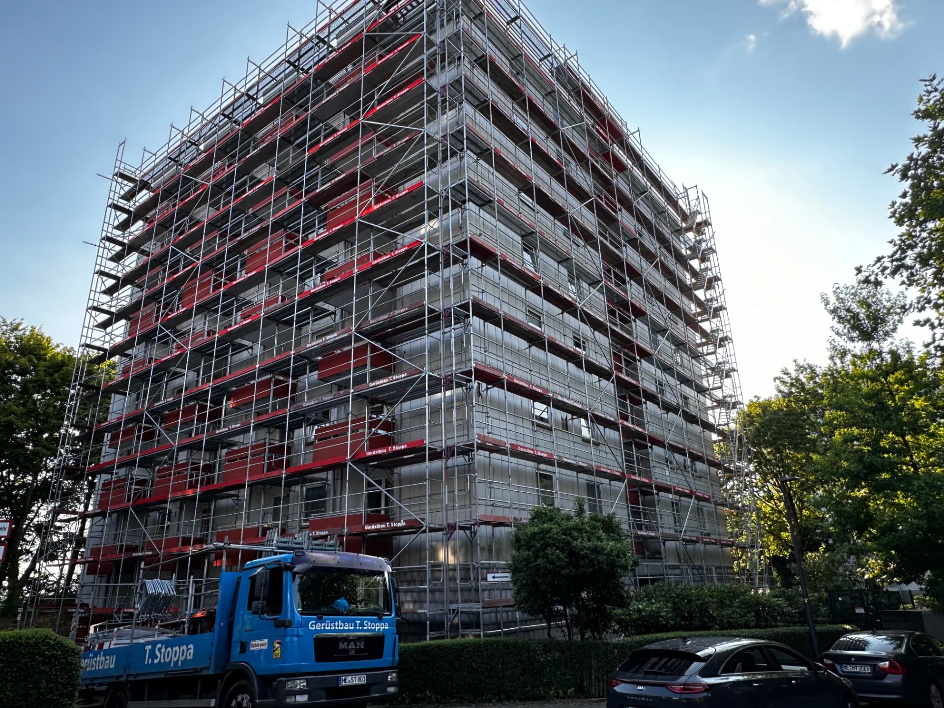 Echtes Stoppa-Projekt: vollflächig eingerüstetes Mehrfamilienhaus mit blauem Gerüstbau-Stoppa-Lkw